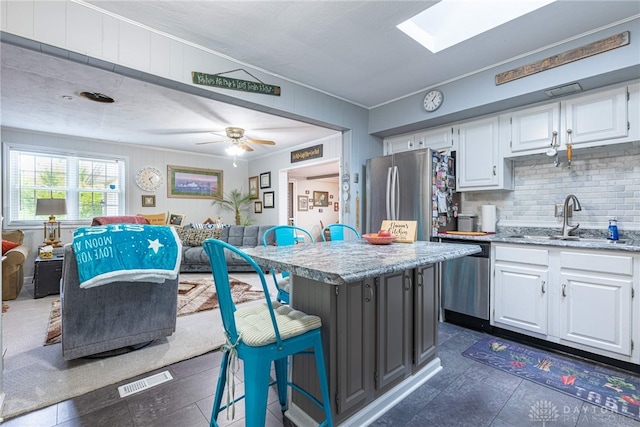 1808 Burnside Dr, Miamisburg, OH 45342 - kitchen featuring appliances with stainless steel finishes, open floor plan, white cabinets, crown molding, and a breakfast bar area