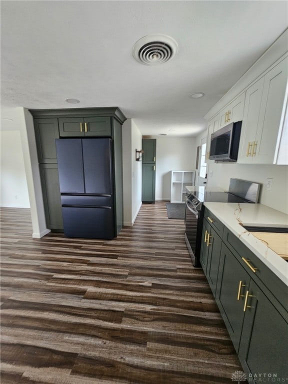 283 Moore St, Lewisburg, OH 45338 - kitchen with freestanding refrigerator, stainless steel microwave, electric stove, dark wood-style floors, and light stone countertops