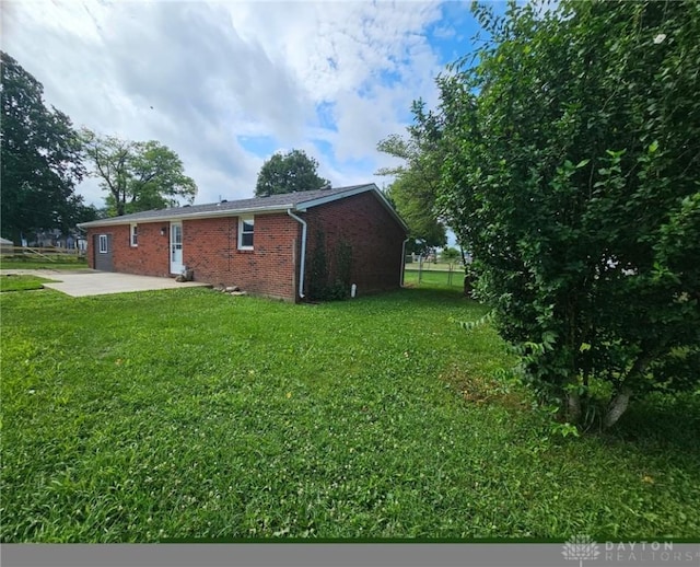 283 Moore St, Lewisburg, OH 45338 - view of home's exterior with a patio, brick siding, and a lawn