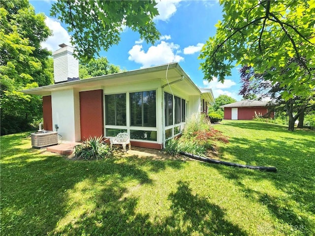 851 E County Line Rd, Springfield, OH 45502 - rear view of house featuring a chimney, a lawn, and a sunroom
