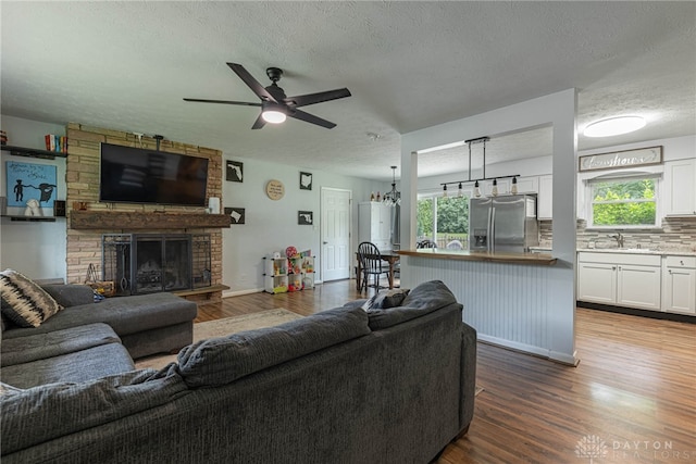3442 Longleaf Ave, Beavercreek, OH 45430 - living area featuring dark wood-style flooring, a ceiling fan, a textured ceiling, and a stone fireplace