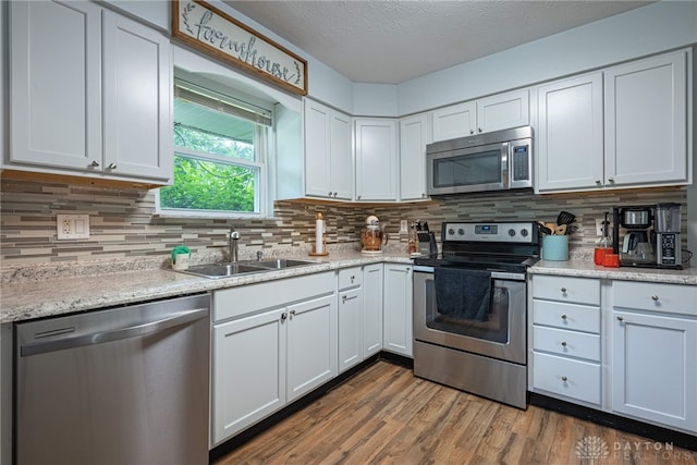 3442 Longleaf Ave, Beavercreek, OH 45430 - kitchen with stainless steel appliances, wood finished floors, white cabinetry, tasteful backsplash, and a textured ceiling
