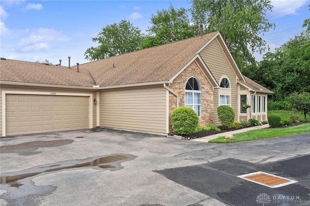 2782 Stefan Pl, Beavercreek, OH 45431 - view of front of home with stone siding, driveway, an attached garage, and roof with shingles
