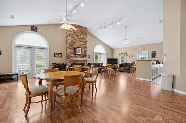 2782 Stefan Pl, Beavercreek, OH 45431 - dining area with a fireplace, ceiling fan, rail lighting, high vaulted ceiling, and wood finished floors