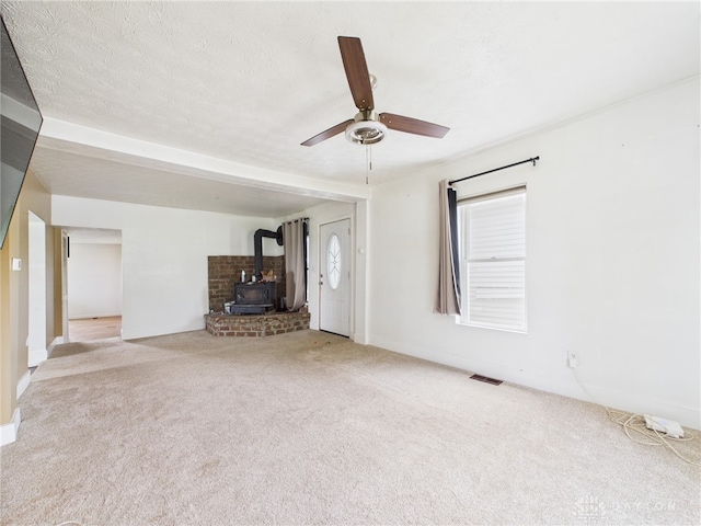 491 Frazers Rd, West Manchester, OH 45382 - unfurnished living room with a wood stove, carpet, a ceiling fan, healthy amount of natural light, and a textured ceiling