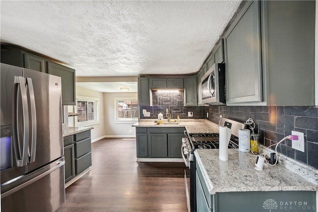 3579 Alberta St, Columbus, OH 43228 - kitchen featuring appliances with stainless steel finishes, a textured ceiling, dark wood-style floors, decorative backsplash, and light stone counters