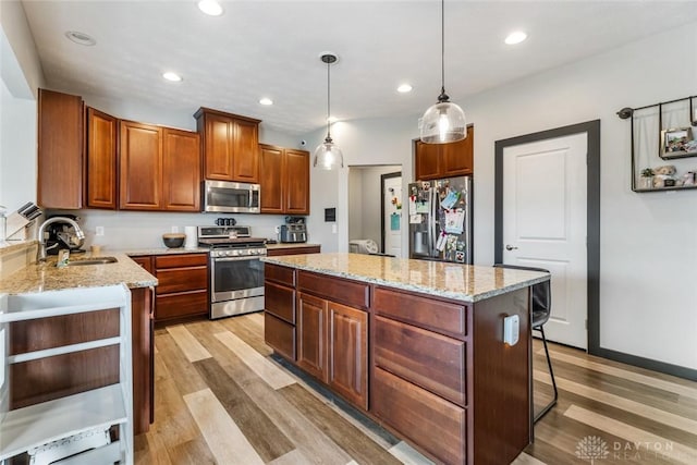 1950 Stone Creek Blvd, Clearcreek Twp, OH 45458 - kitchen with appliances with stainless steel finishes, a kitchen island, light wood finished floors, light stone counters, and decorative light fixtures