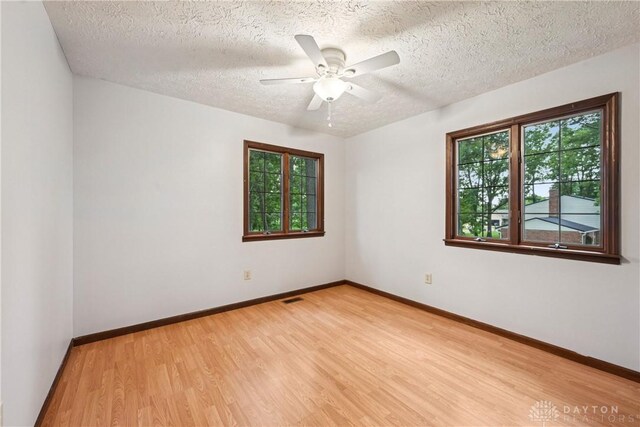 4595 Comanchee Trl, Silver Creek Twp, OH 45335 - empty room featuring plenty of natural light, light wood-style flooring, a textured ceiling, and ceiling fan