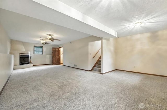 51 Jill Dr, Germantown, OH 45327 - unfurnished living room with stairway, light colored carpet, a fireplace, ceiling fan, and a textured ceiling
