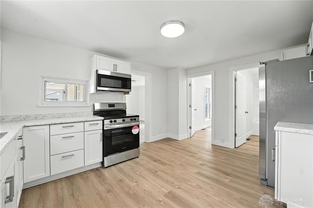 804 S Walnut St, Troy, OH 45373 - kitchen with stainless steel appliances, light wood-style flooring, white cabinetry, and light stone countertops