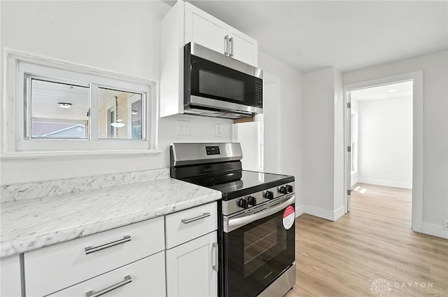 804 S Walnut St, Troy, OH 45373 - kitchen featuring appliances with stainless steel finishes, white cabinets, light wood-type flooring, and light stone countertops
