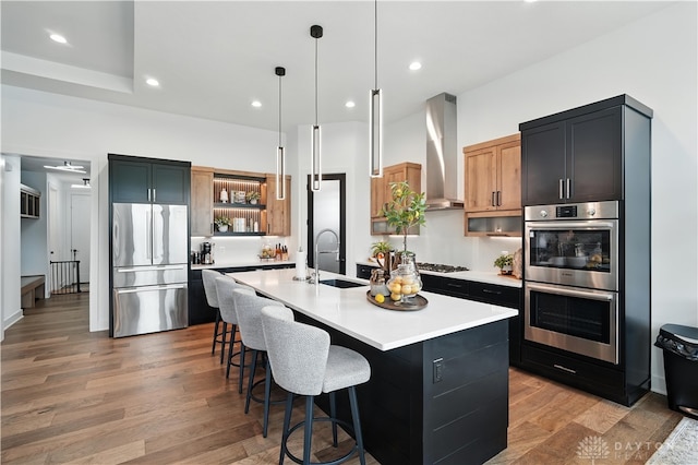 1241 Normandy Rue, Centerville, OH 45458 - kitchen with appliances with stainless steel finishes, wall chimney range hood, a breakfast bar area, light wood finished floors, and light countertops