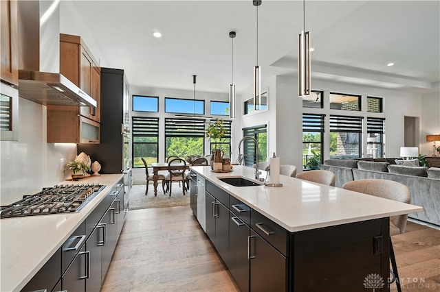 1241 Normandy Rue, Centerville, OH 45458 - kitchen featuring wall chimney exhaust hood, appliances with stainless steel finishes, light wood-style floors, light countertops, and a breakfast bar
