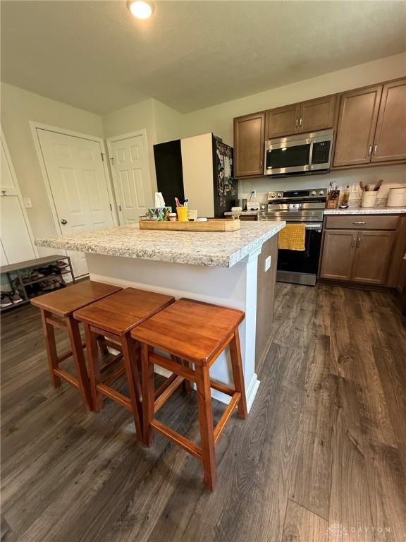 562 Maxwell Ct, Germantown, OH 45327 - kitchen with appliances with stainless steel finishes, dark wood finished floors, a kitchen breakfast bar, and a center island