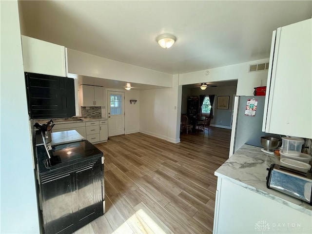 10995 Rockridge Rd, Lewisburg, OH 45338 - kitchen featuring a ceiling fan, white cabinets, light wood-style floors, freestanding refrigerator, and tasteful backsplash