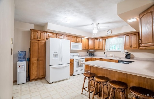 4267 W Wenger Rd, Clayton, OH 45315 - kitchen featuring white appliances, a peninsula, a kitchen bar, light floors, and light countertops