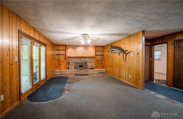 4267 W Wenger Rd, Clayton, OH 45315 - unfurnished living room featuring wood walls, ceiling fan, carpet flooring, and a fireplace