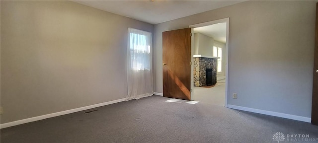 289 Dayton Ave, Xenia, OH 45385 - spare room featuring healthy amount of natural light, a stone fireplace, and dark carpet