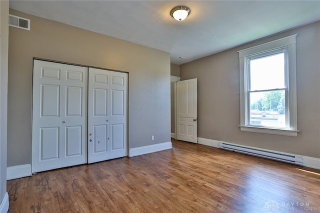 15 Bertus St, Cincinnati, OH 45217 - unfurnished bedroom featuring a baseboard radiator, wood finished floors, and a closet