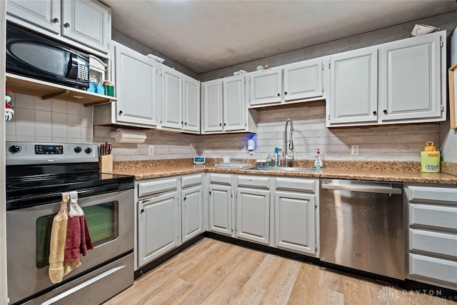 1227 Fyffe Ave, New Carlisle, OH 45344 - kitchen with appliances with stainless steel finishes, light wood-type flooring, decorative backsplash, light countertops, and white cabinets
