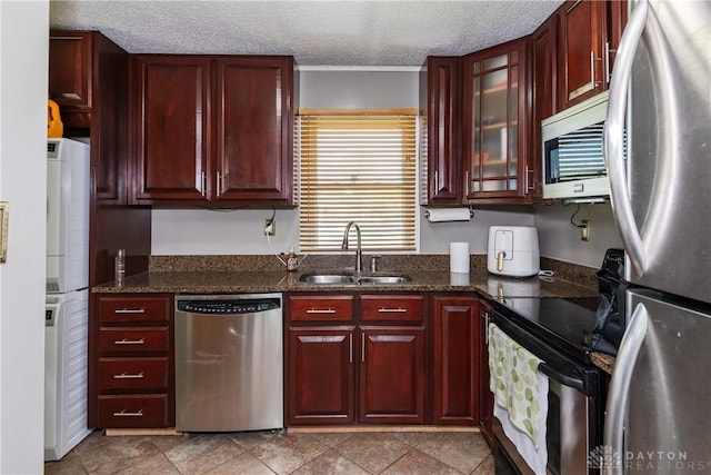 1221 Highview Dr, Fairborn, OH 45324 - kitchen with stainless steel appliances, reddish brown cabinets, a textured ceiling, dark stone counters, and glass insert cabinets