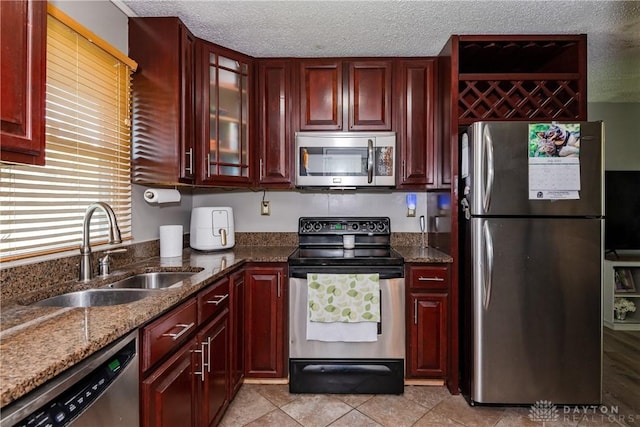 1221 Highview Dr, Fairborn, OH 45324 - kitchen with appliances with stainless steel finishes, reddish brown cabinets, dark stone countertops, a textured ceiling, and glass insert cabinets