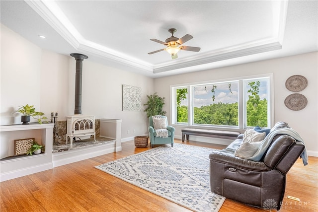 1590 Fairground Rd, Xenia, OH 45385 - living room featuring a raised ceiling, a wood stove, wood finished floors, ceiling fan, and ornamental molding