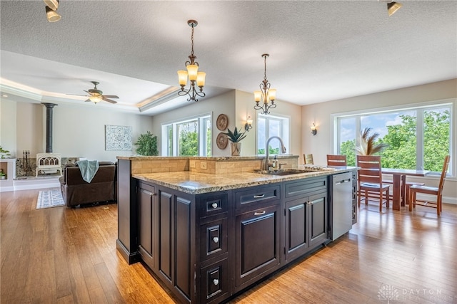1590 Fairground Rd, Xenia, OH 45385 - kitchen featuring stainless steel dishwasher, light wood-type flooring, a textured ceiling, hanging light fixtures, and a center island with sink