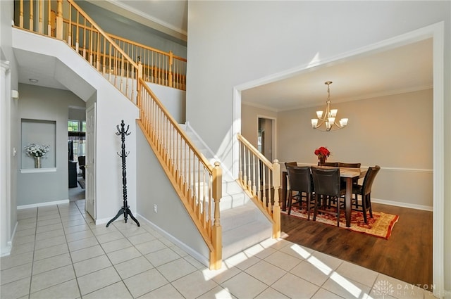 2435 Forest Oaks Dr, Beavercreek, OH 45431 - staircase featuring tile patterned flooring, a chandelier, ornamental molding, and a towering ceiling