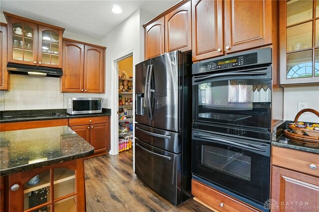 2435 Forest Oaks Dr, Beavercreek, OH 45431 - kitchen with black appliances, under cabinet range hood, dark wood-style floors, backsplash, and dark stone counters