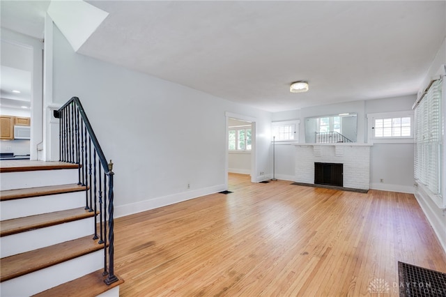 25 Laura Ave, Dayton, OH 45405 - unfurnished living room featuring plenty of natural light, light wood-style flooring, stairway, and a fireplace