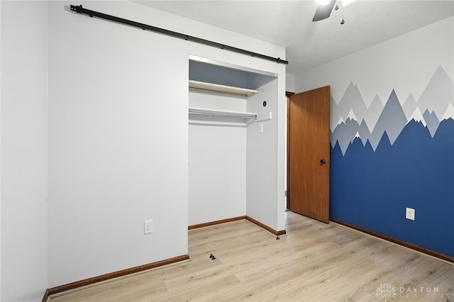 5 Bayberry Dr, Springboro, OH 45066 - unfurnished bedroom with a barn door, wood finished floors, ceiling fan, and a closet