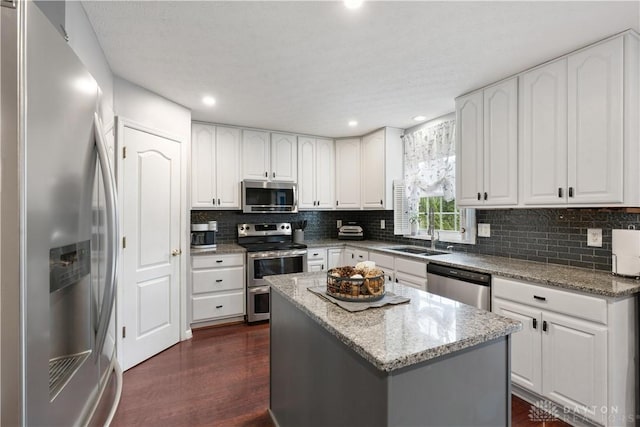 395 Victoria Pl, Waynesville, OH 45068 - kitchen with stainless steel appliances, dark wood-style floors, backsplash, light stone countertops, and a kitchen island