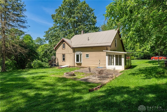 989 Ogden Rd, Adams Twp, OH 45177 - back of property featuring a patio area, a lawn, a metal roof, an outdoor fire pit, and a chimney