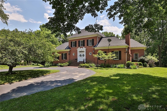 11 Peterson Pl, Wilmington, OH 45177 - colonial inspired home featuring a chimney, a front yard, brick siding, and curved driveway