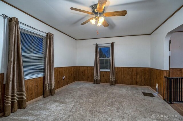 718 Hook Rd, Xenia, OH 45385 - empty room with a wainscoted wall, arched walkways, wood walls, a ceiling fan, and carpet floors