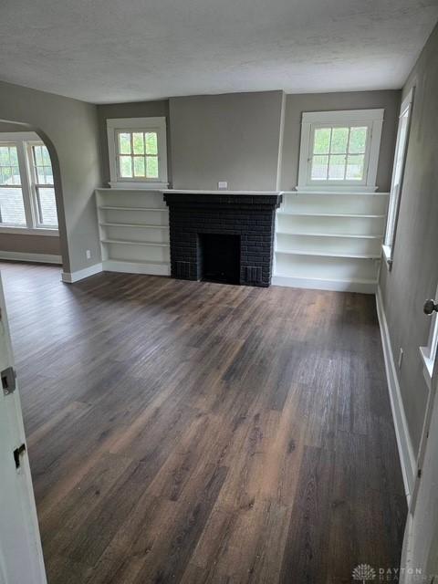 2324 Eastview Unit 2322, Dayton, OH 45405 - unfurnished living room featuring dark wood-style flooring, a fireplace, a textured ceiling, and arched walkways