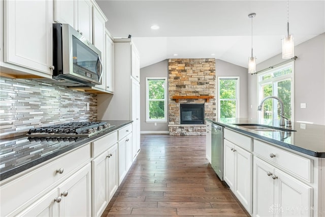 225 Woodstream Dr, Springboro, OH 45066 - kitchen featuring stainless steel appliances, lofted ceiling, dark wood finished floors, a stone fireplace, and backsplash