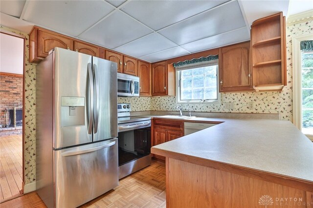 798 Carini Ln, Cincinnati, OH 45218 - kitchen featuring appliances with stainless steel finishes, brown cabinetry, open shelves, light countertops, and wallpapered walls