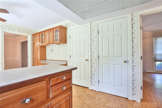 798 Carini Ln, Cincinnati, OH 45218 - kitchen featuring wallpapered walls, glass insert cabinets, ornamental molding, light countertops, and brown cabinets