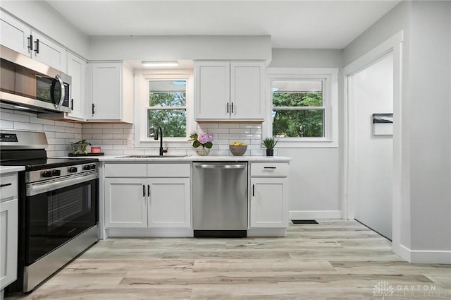 1378 Standish Ave, Riverside, OH 45432 - kitchen featuring stainless steel appliances, light countertops, decorative backsplash, white cabinetry, and light wood-type flooring