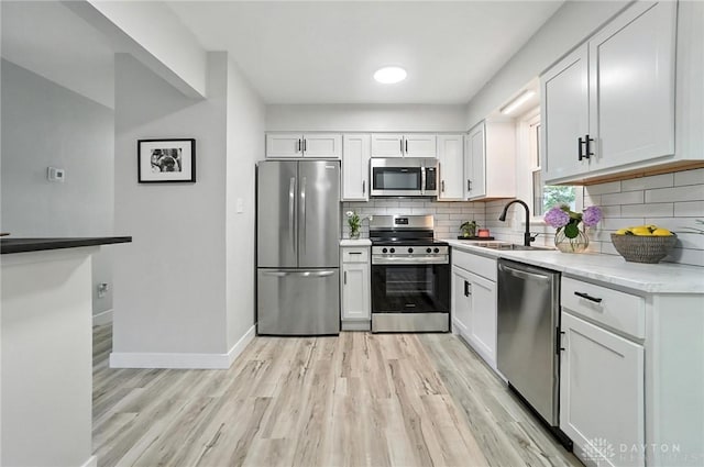 1378 Standish Ave, Riverside, OH 45432 - kitchen with appliances with stainless steel finishes, light wood finished floors, tasteful backsplash, white cabinets, and light countertops