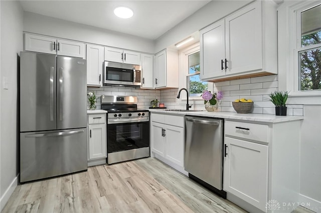 1378 Standish Ave, Riverside, OH 45432 - kitchen with appliances with stainless steel finishes, white cabinetry, light wood-style flooring, and decorative backsplash