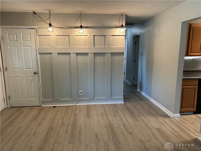 103 W Boitnott Dr, Englewood, OH 45322 - kitchen with light wood-style floors, brown cabinetry, and decorative light fixtures