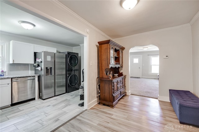 541 E Main St, Xenia, OH 45385 - kitchen with appliances with stainless steel finishes, stacked washer and clothes dryer, arched walkways, light wood finished floors, and ornamental molding