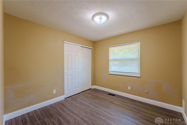 1110 Langdale Ave, New Carlisle, OH 45344 - unfurnished bedroom with dark wood-style flooring, a closet, and a textured ceiling
