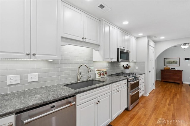 69 Bridge St, Cedarville Twp, OH 45314 - kitchen featuring stainless steel appliances, white cabinetry, decorative backsplash, light wood finished floors, and dark stone counters