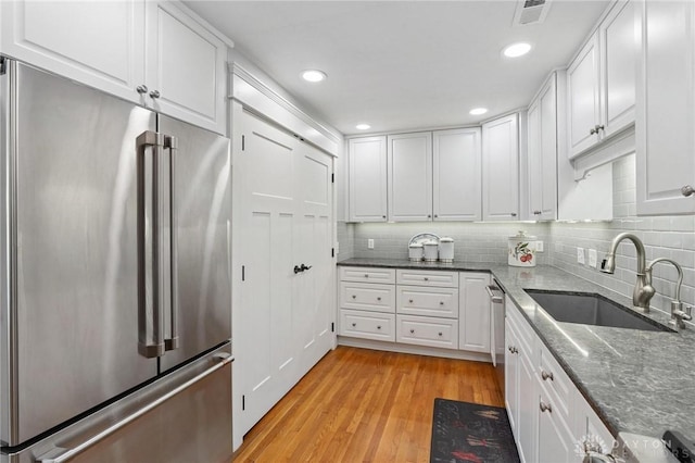69 Bridge St, Cedarville Twp, OH 45314 - kitchen with stainless steel appliances, white cabinets, light wood-type flooring, tasteful backsplash, and dark stone countertops