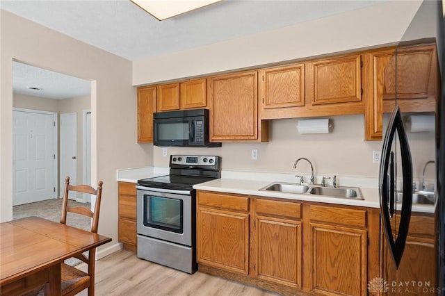 442 Kirkwood Dr, Fairborn, OH 45324 - kitchen featuring black appliances, light countertops, brown cabinetry, and light wood-style flooring