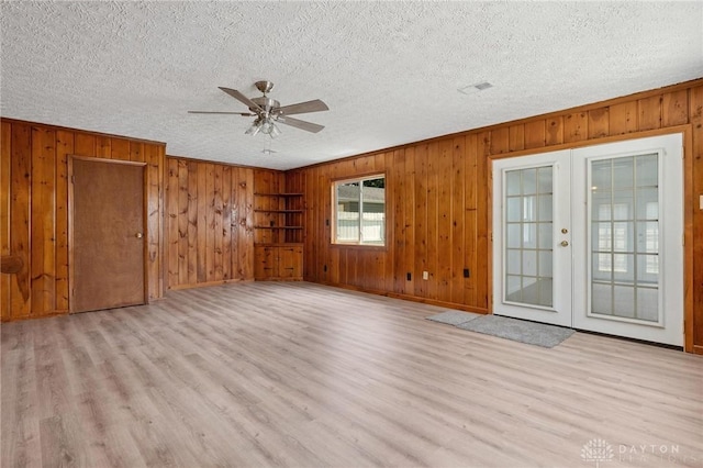 442 Kirkwood Dr, Fairborn, OH 45324 - empty room with french doors, wooden walls, light wood-type flooring, ceiling fan, and a textured ceiling